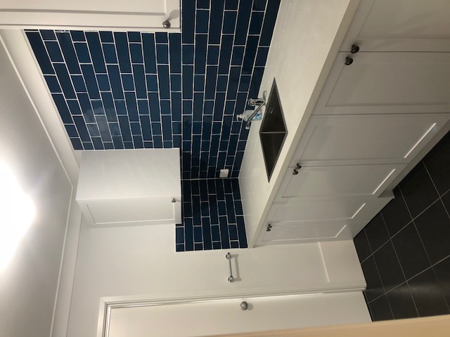 New laundry with navy subway tiles, shaker cabinetry and stone benchtop
